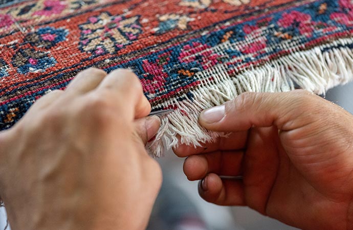 a professional repairing a rug fringe