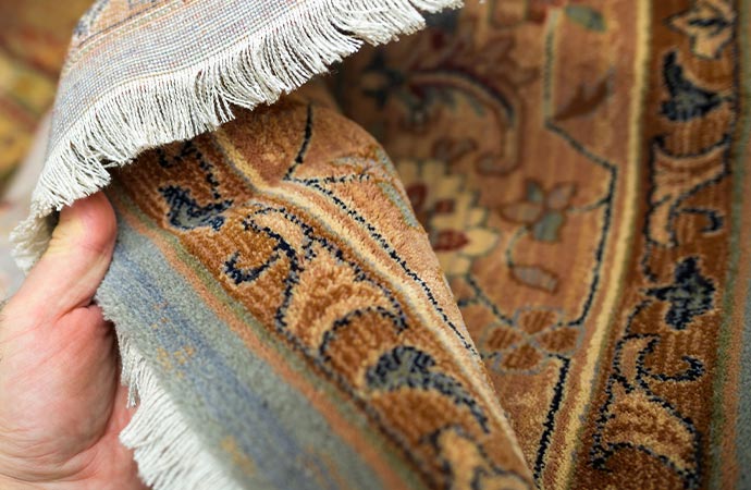 a person inspecting a rug