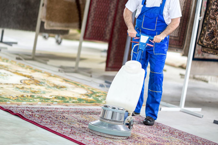 A worker is inspecting a rug during the cleaning process